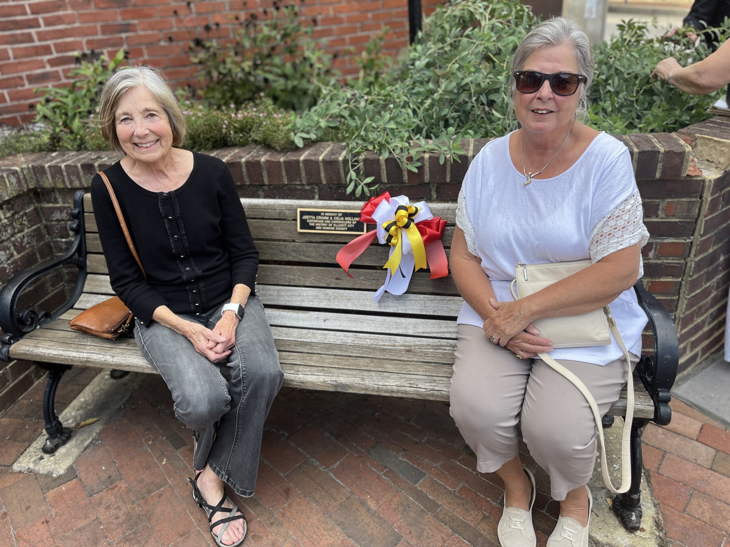 HEC, Inc. Secretary, Kathy Younkin and Co Chair of EC 250 (who provided the funding for the bench plaques), Victoria Goodman sit upon the bench dedicated to historians Joetta Cramm and Celia Holland.